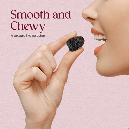 Ajwa dates held between fingers, dark wrinkled fruit with glossy skin
